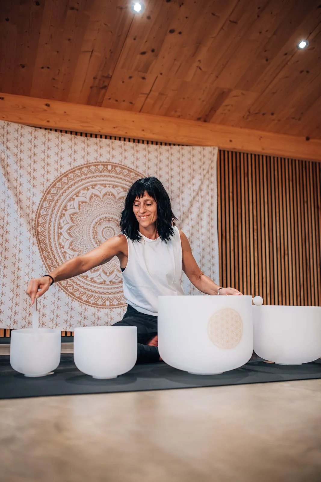 Katrin mit Klangschalen vor der Mandala-Wand